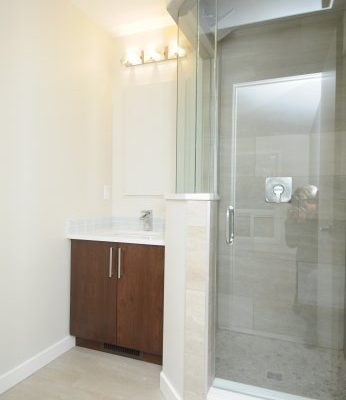 Single vanity and glass shower installed by Refine Renovations